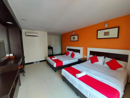 two beds in a hotel room with orange walls at HOTEL SAHARA SDN BHD in Rawang