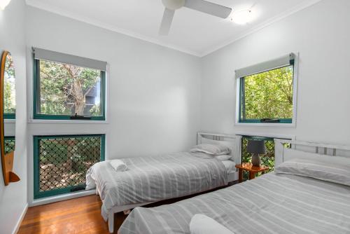 two beds in a room with two windows at Tchoomooroo in Point Lookout