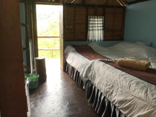 a bedroom with a bed in a room with a window at Phu Plai Fah in Chiang Rai