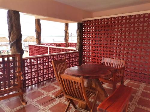 a table and chairs in a room with a red wall at Hotel El Perico Marinero in Río Lagartos