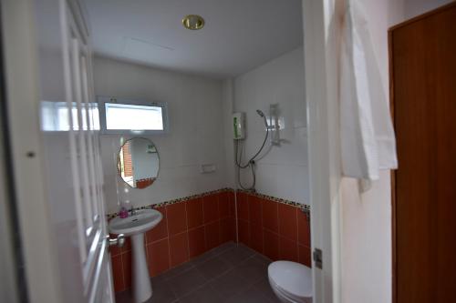ein Badezimmer mit einem Waschbecken, einem WC und einem Spiegel in der Unterkunft KT Knight Hotel in Surin