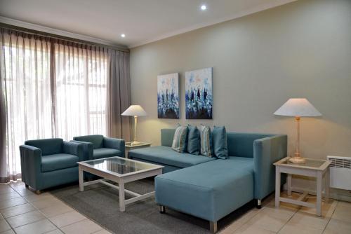 a living room with blue couches and a table at ANEW Resort Hunters Rest Rustenburg in Rustenburg