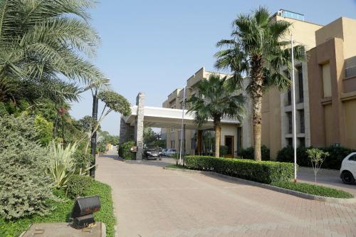a building with palm trees next to a street at Tivoli Garden Resort in New Delhi