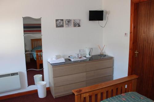 a bedroom with a dresser with a tv on the wall at The Barn Lodge in Stirling