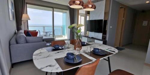 - un salon avec une table et des chaises offrant une vue sur l'océan dans l'établissement Riviera Jomtien by Zoom Pattaya 1, à Jomtien Beach