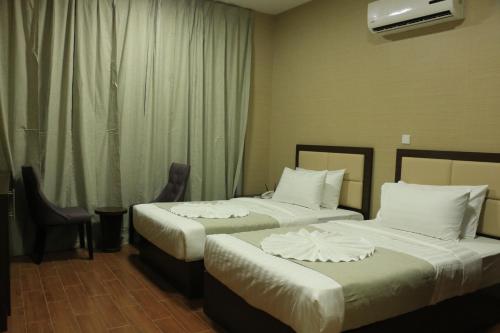 a hotel room with two beds with white sheets at Alpha Suites Hotel in Salalah