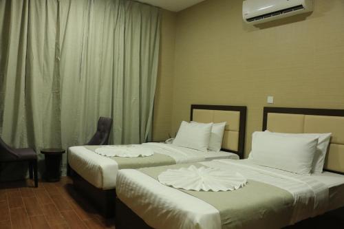 a hotel room with two beds with white sheets at Alpha Suites Hotel in Salalah
