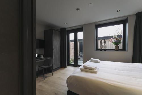 a bedroom with a bed and a desk and a window at Hotel Bell in Zandvoort