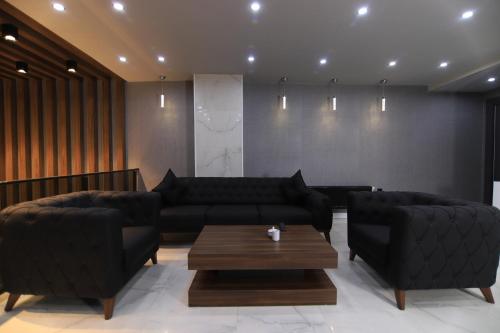 a living room with two black couches and a coffee table at SARDUR HOTEL in Bostaniçi