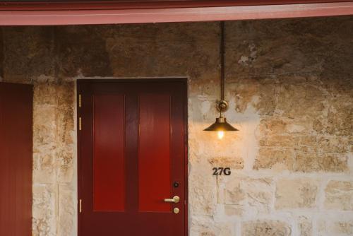 a red door next to a brick wall with a light at Garde and Warders Hotel in Fremantle