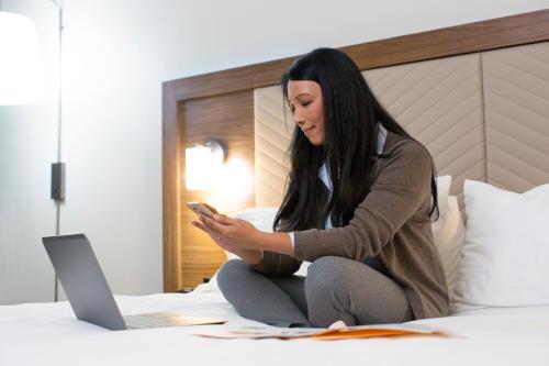 a woman sitting on a bed using a laptop at Holiday Inn Express London Victoria, an IHG Hotel in London