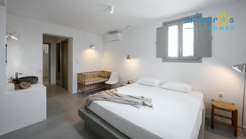 a white bedroom with a bed and a window at Antiparos Homes in Antiparos
