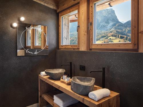 Baño con 2 lavabos en una encimera con ventanas en Sotciastel Antico Chalet, en Badia