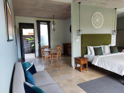 a bedroom with a bed and a table and chairs at Bali Sila Bisma in Ubud