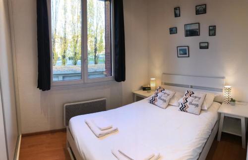 1 dormitorio con 1 cama blanca y ventana en LES ÎLES - Parking, Balcon, Netflix & PS4! en Annecy