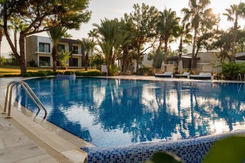 a large swimming pool with palm trees and a building at Hillstone Bodrum Hotel & Spa in Bodrum City