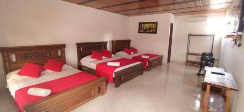 a bedroom with two beds with red pillows in it at Hotel campestre la Maria in Villavicencio