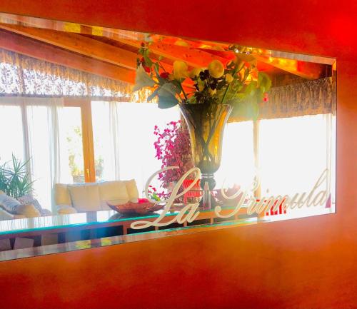 a vase with flowers on a table in front of a window at Hotel La Primula in Corigliano Calabro