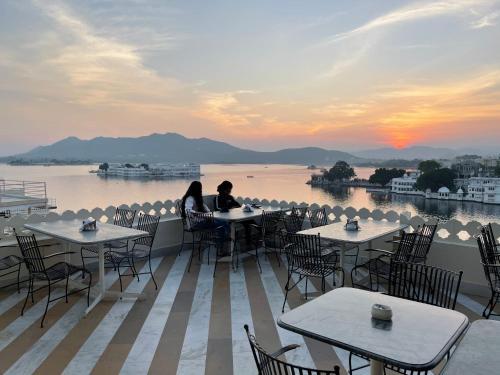 
two people sitting at a table in front of a large body of water at Jaiwana Haveli in Udaipur

