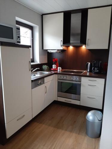 a kitchen with white cabinets and a stove top oven at Fewo Zum Sonnenschein in Simmerath
