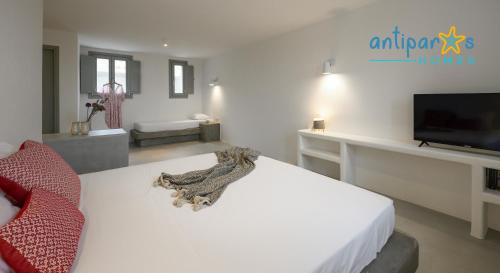 a bedroom with a white bed and a flat screen tv at Antiparos Homes in Antiparos Town