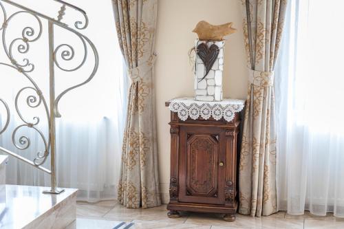a clock sitting on a stand in a room with curtains at Vitalhotel Marienhof in Velden am Wörthersee