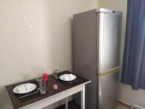 uma mesa com dois pratos e um frigorífico em Уютная квартира em Rivne