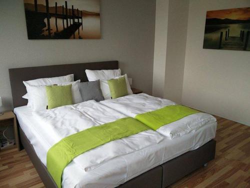 uma cama grande com lençóis verdes e brancos num quarto em Hotel Art Inn Dinslaken em Dinslaken