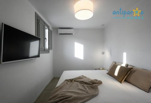 a white bedroom with a bed and a flat screen tv at Antiparos Homes in Antiparos Town