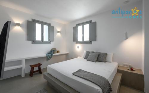 a bedroom with a white bed with two windows at Antiparos Homes in Antiparos Town