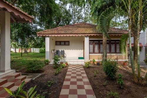 a small house with a checkered walkway at KSTDC Hotel Mayura Velapuri Belur in Belūr