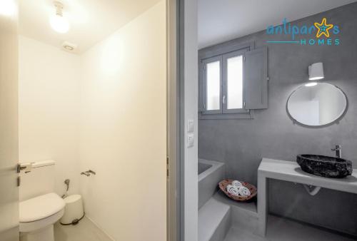 a bathroom with a sink and a toilet and a mirror at Antiparos Homes in Antiparos Town