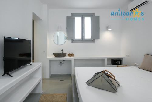 a white living room with a table and a television at Antiparos Homes in Antiparos Town