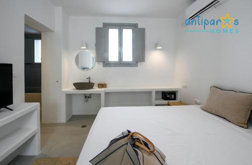 a white bedroom with a white bed and a mirror at Antiparos Homes in Antiparos Town