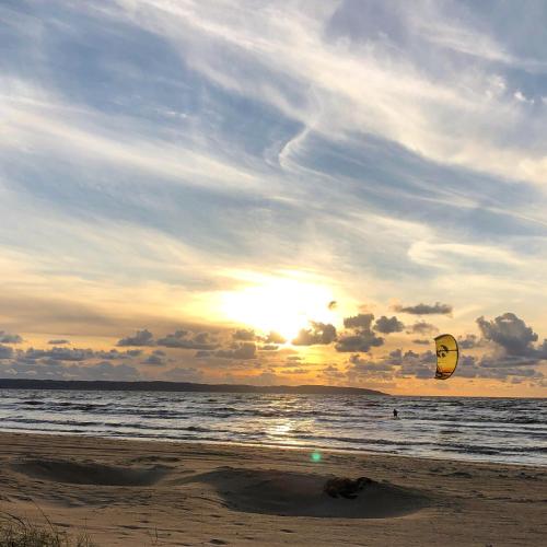 a person flying a kite on the beach at sunset at Mellbystrand Björkvägen Apartment in Mellbystrand
