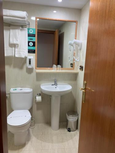 a bathroom with a toilet a sink and a mirror at Hotel Los Templarios in Ponferrada