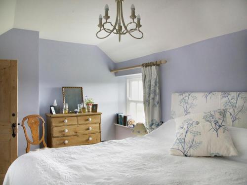 a bedroom with a white bed with a dresser and a window at Higher Tresmorn Farm in Crackington Haven