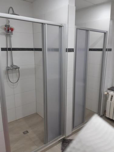2 cabines de douche en verre dans une salle de bains blanche dans l'établissement Apartments Markus & Annika (über 2 Etagen), à Bitterfeld