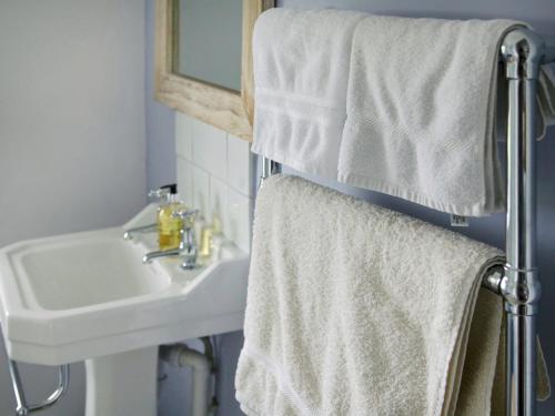 La salle de bains est pourvue d'un lavabo et de serviettes sur un porte-serviettes. dans l'établissement Higher Tresmorn Farm, à Crackington Haven