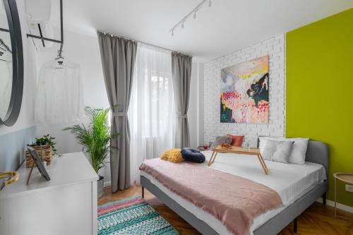 Eden by CityLife Suites في بوخارست: غرفة نوم بجدران خضراء وسرير مع طاولة