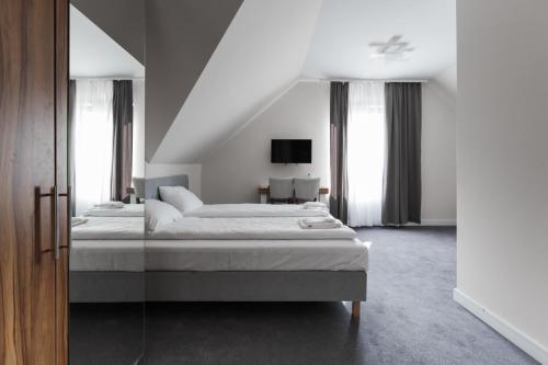 a white bedroom with a bed and windows at Villa Con Amore in Słońsk