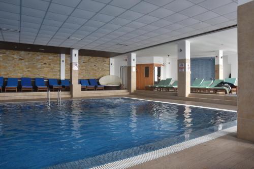 a swimming pool in a hotel with blue chairs at Milmari Apartment 43 Premier Pollo in Kopaonik
