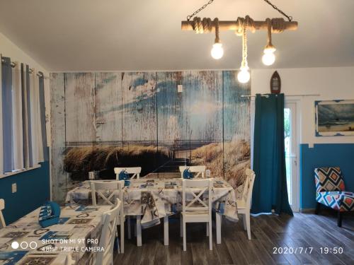 een eetkamer met witte tafels en een schilderij aan de muur bij Blue Bungalow Jurilovca in Jurilovca