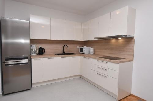 a kitchen with white cabinets and a stainless steel refrigerator at Apartments Danica in Primošten