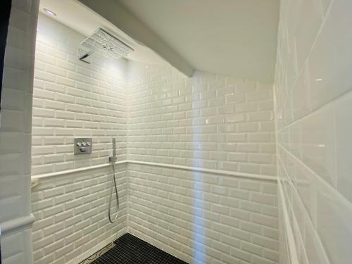 uma casa de banho com chuveiro e paredes de tijolos brancos em 21 Dupaty Le Studio em La Rochelle