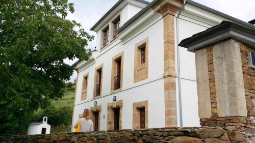 uma mulher em pé em frente a um edifício em Apartamentos Rurales Los Mazos em Boal