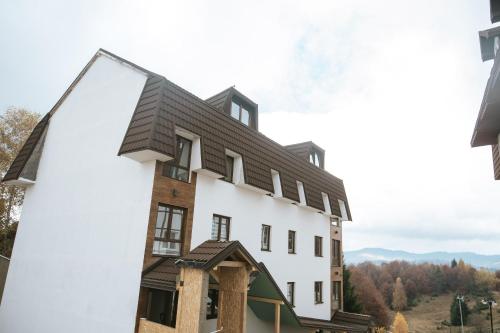 una rappresentazione di un edificio bianco con tetto nero di Kraljevi Konaci -Apartmani Bajka a Kopaonik