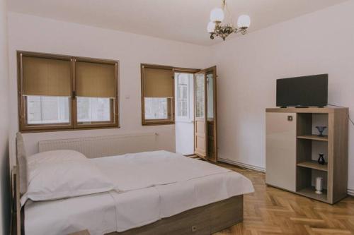 1 dormitorio con 1 cama blanca y TV en Predoi's Place, en Sinaia