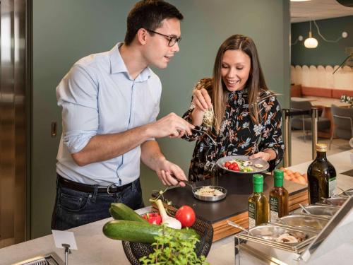 a man and a woman preparing food in a kitchen at Adagio access Brussels Delta in Brussels