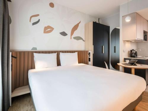 a bedroom with a large white bed and a kitchen at Adagio access Brussels Delta in Brussels